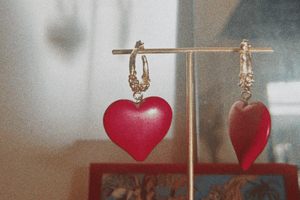 créoles en bronze plaqué or faites de multiples granulations irrégulières, ornées d'une graine en forme de coeur rouge écarlate, collection Esther de Carthage, fabrication artisanale française